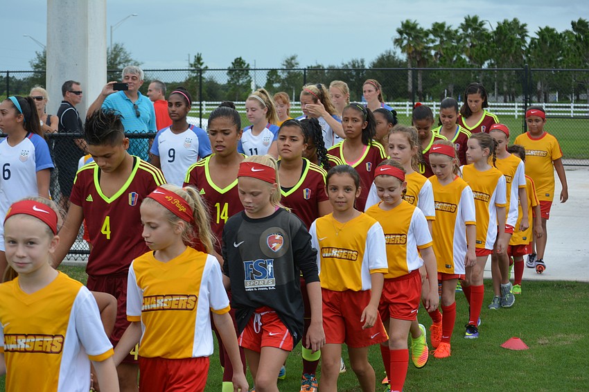 Chargers players escort Venezuela's players on the field.