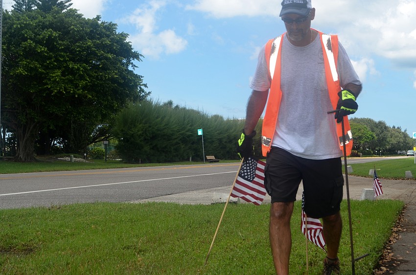 Mark Richardson places an American flag along GMD on the afternoon of Sept. 9.