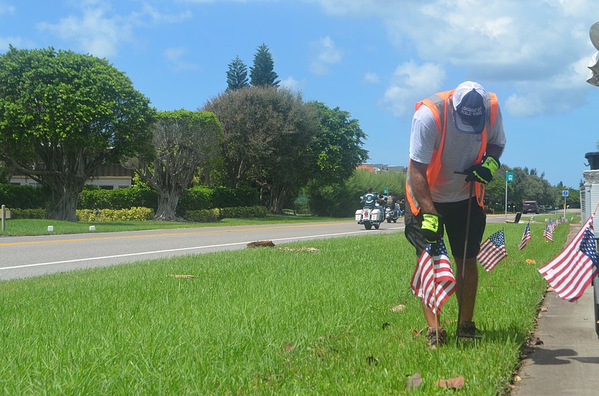 Mark Richardson sticks one of the 2,977 American flags into the ground along GMD.