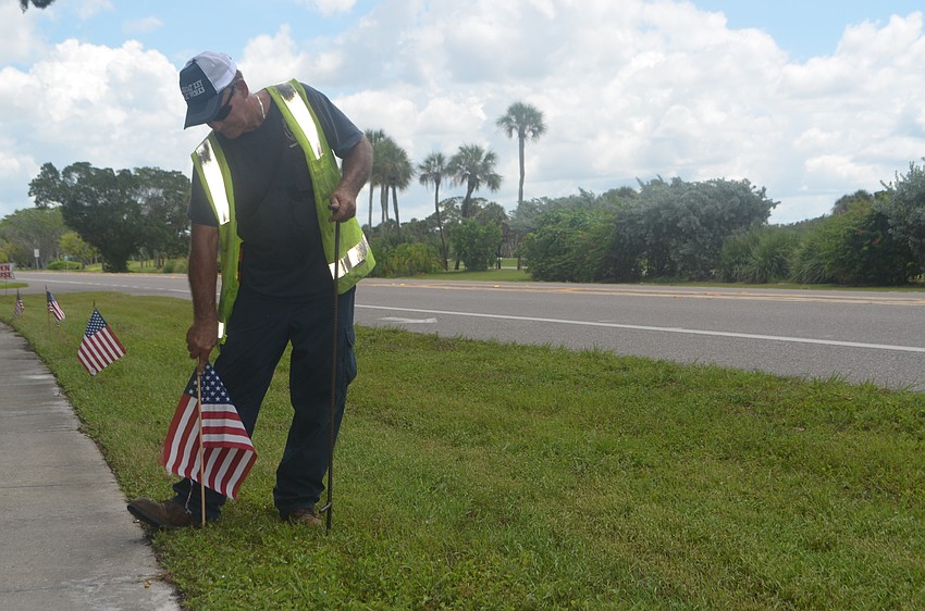 Mike Ball places an American flag on the grass alongside GMD. This flag was just one of 2,977 placed in honor of those who lost their lives on 9/11.