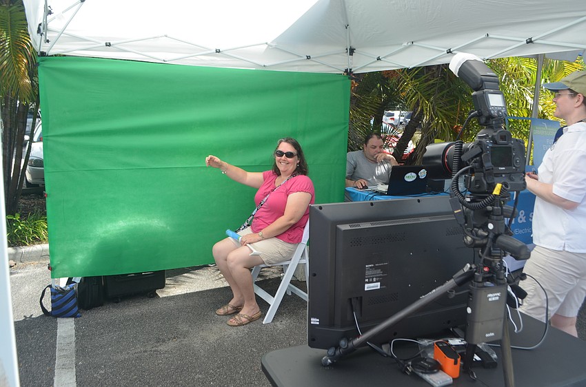 Pam Anthofer sits in front of green screen and pretends she’s driving an electric vehicle during Mote Marine Laboratory and Aquarium’s 5th annual Electrify the Island.