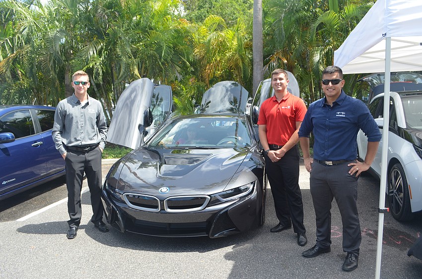 Taylor Marshall, Austin Adams, and Jonatan Escobar of BMW of Sarasota stand next to a BMW i8.