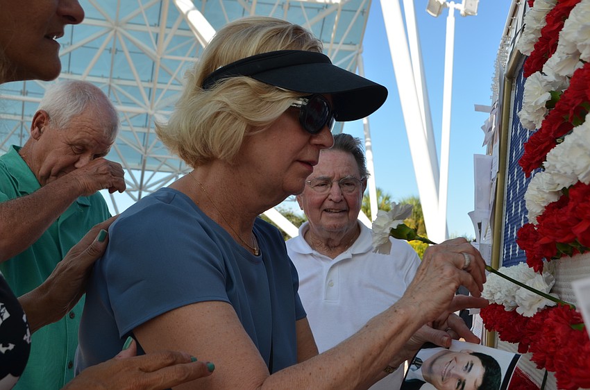 Diane Combs places a white carnation into an arrangement that formed the American flag to honor victims of the 9/11 attacks.