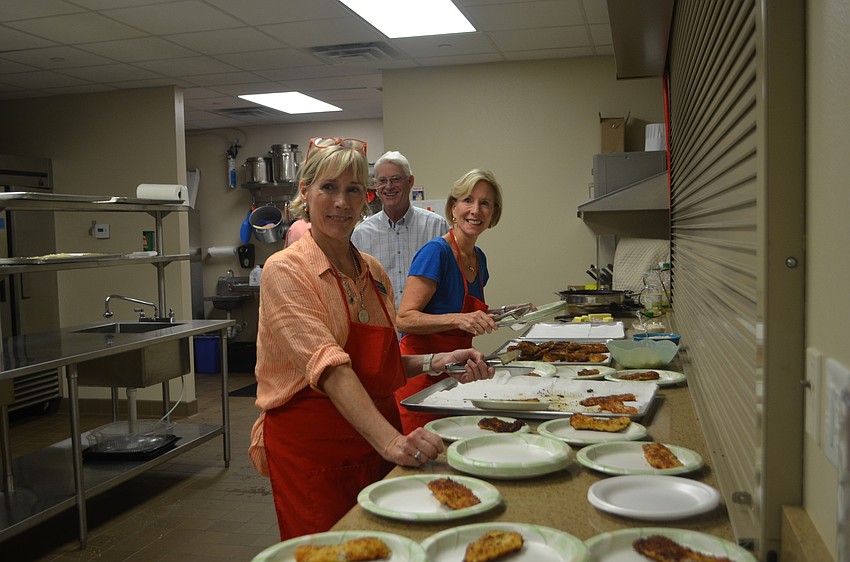Lutie Uihlein, George Rauch and Sally Rauch get the plates ready before guests line up for food.