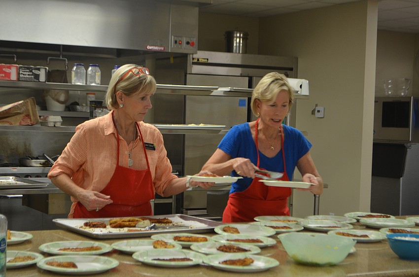 Lutie Uihlein and Sally Rauch dish out plates of fish to Christ Church members.