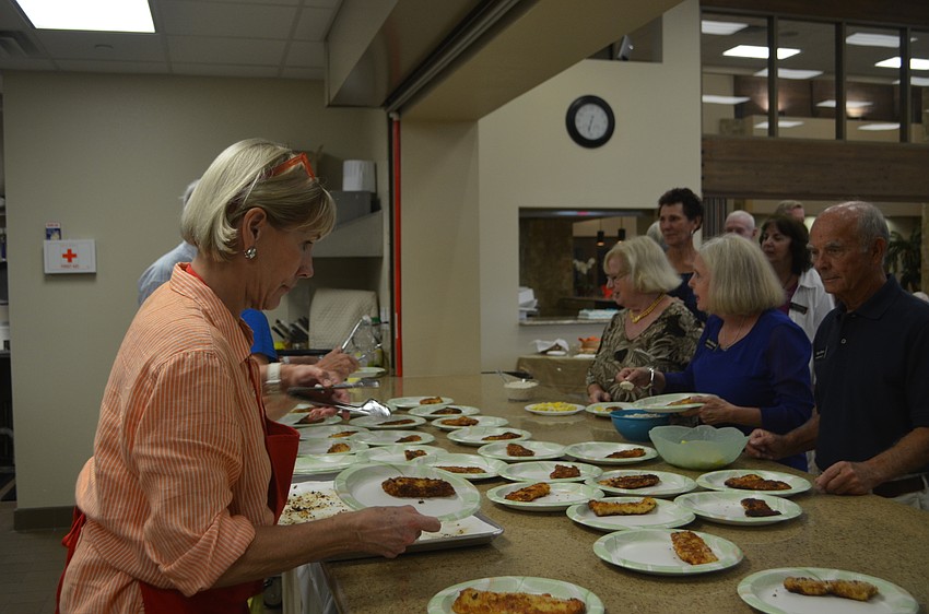 Lutie Uihlein hands out plates as Christ Church members wait for their food.
