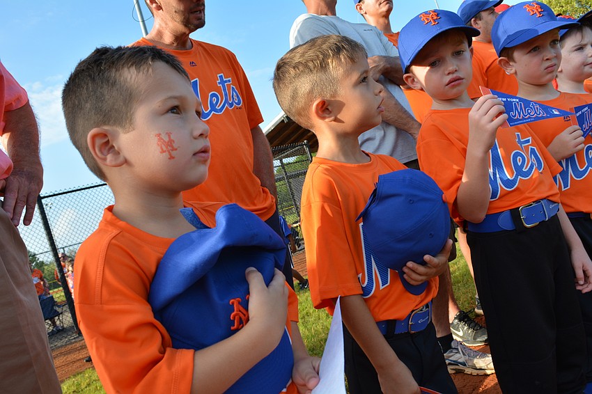 Levi Johnson, 4, left, and his teammates stand for the national anthem.