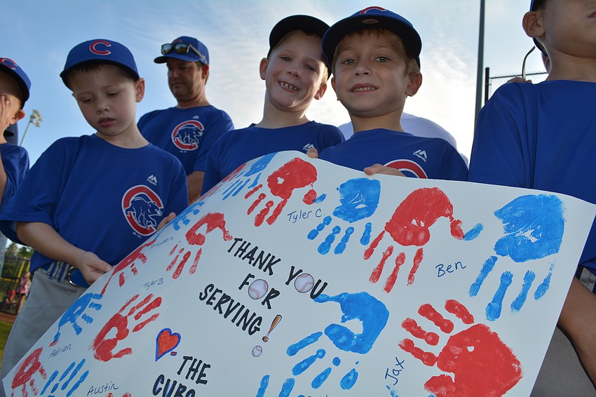 Brayden Gagnon, Knox Hammett and Jaxson Griffin show off their team's sign, marked with handprints of the players.