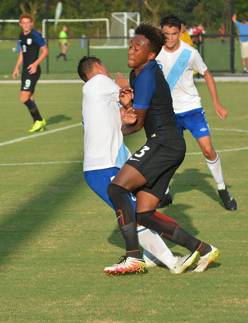 Soccer turns into football as Christopher Gloster of the U.S. runs over Guatemala's Adrian Paredes.