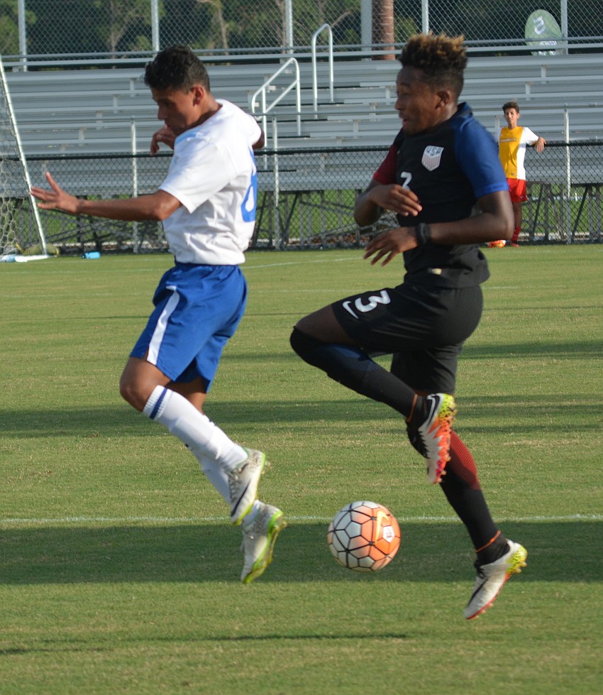Guatemala's Ronaldo Velasquez and Christopher Gloster of the U.S. appear to be doing a dance step as they vie for the ball.