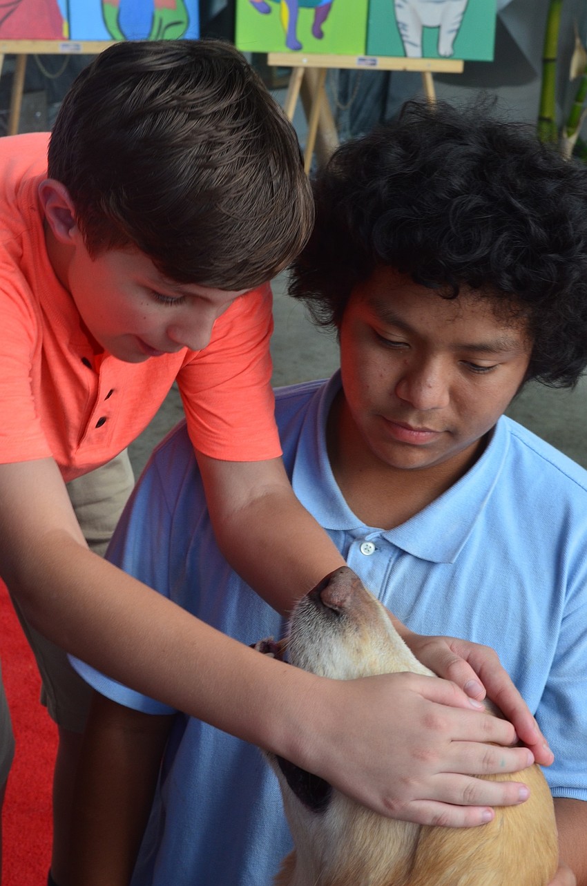 Ethan Lauk, 11, and Diego Taylor, 13, pet Hooch, a service dog that attended the Giving Challenge.