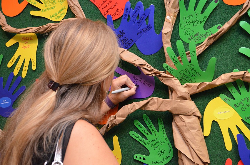 Lori Downing, North River Care, adds to the wall of handprints.
