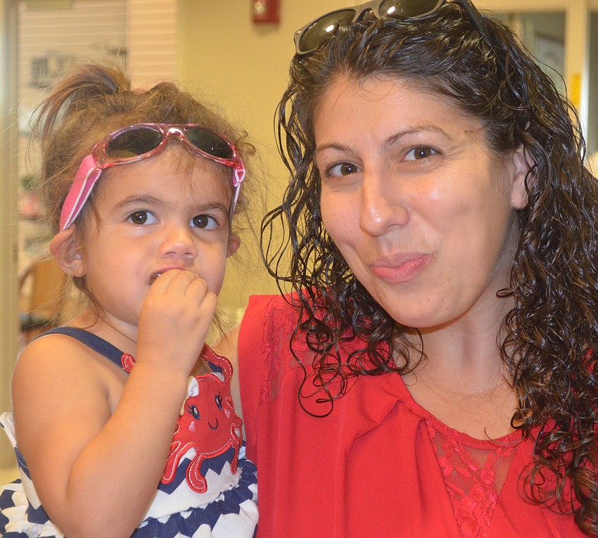 Sarasota's Sofia Jackson, 2, and her mom Andrea Jackson munch on some free snacks at the Health and Wellness Expo.