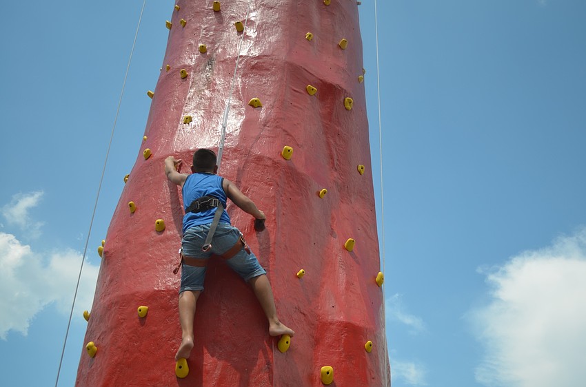 Parrish's Kian Martinez, 9, gets a workout as he climbs to the top of the rock climbing attraction.