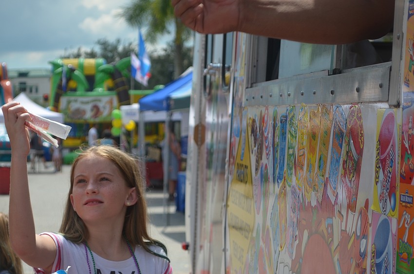 Bradenton's Sienna Munns, 10, grabs a wooden spoon so she can dig in to her ice cream that she bought from the ice cream truck.
