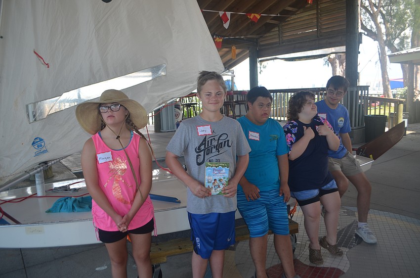 Five members of the Manasota BUDS program stand with a Sunfish sailboat.