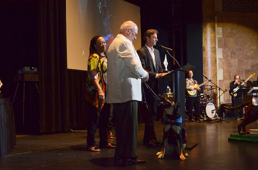 Bob Meade of the Doctors Hospital of Sarasota accepts his third-place award for superhero “Doc” with artist Brenda Robinson. Southeastern Guide Dogs puppy Chef accompanied them with his foster owner Dennis Quinn.