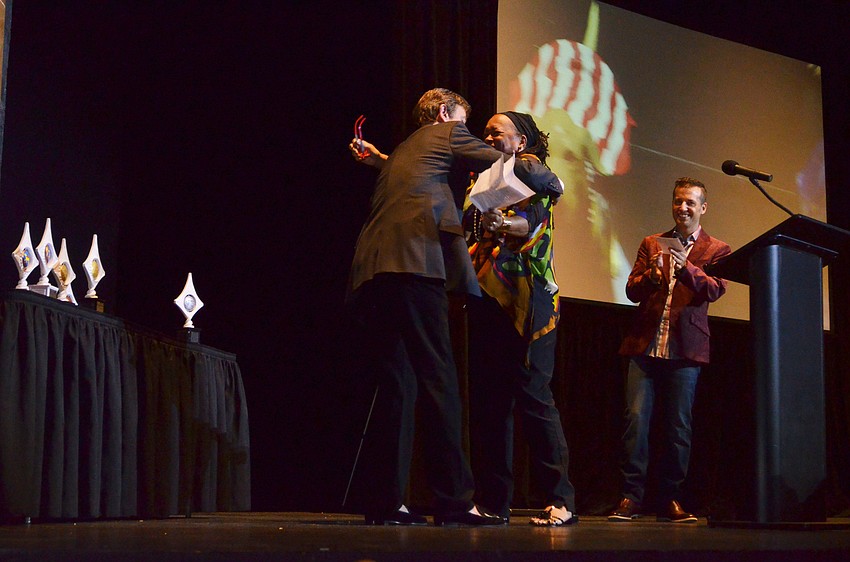 Superhero “Doc” artist Brenda Robinson embraces sponsor Bob Meade after they accepted their third-place award.