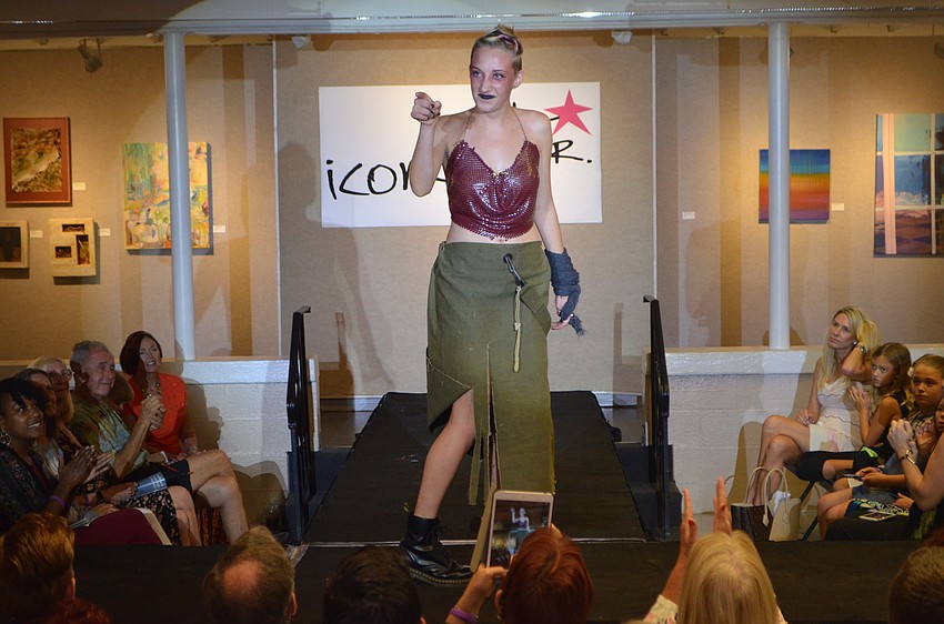 Maezie Kegerreis, 16, points to a loved one in the crowd as she models her piece, “The Lost Girl.” Kegerreis used a vintage purse, antique army duffle bag from 1952 and Halloween decorations to create her ensemble.