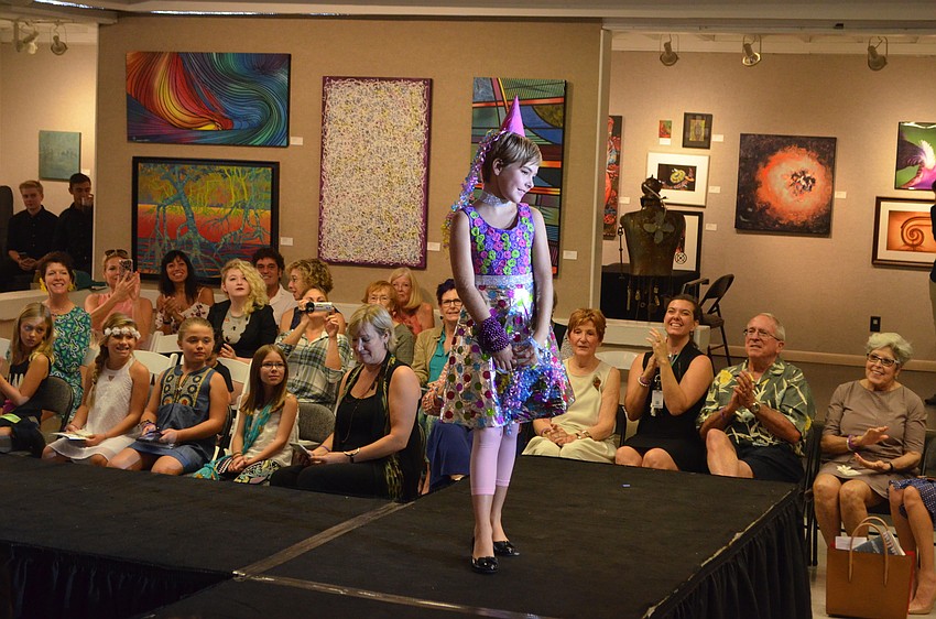 Liv Dickson, 9, smiles for the cameras as she models her piece, “Party Girl,” which she created using ribbon, gift wrap and faux sparkle diamonds.