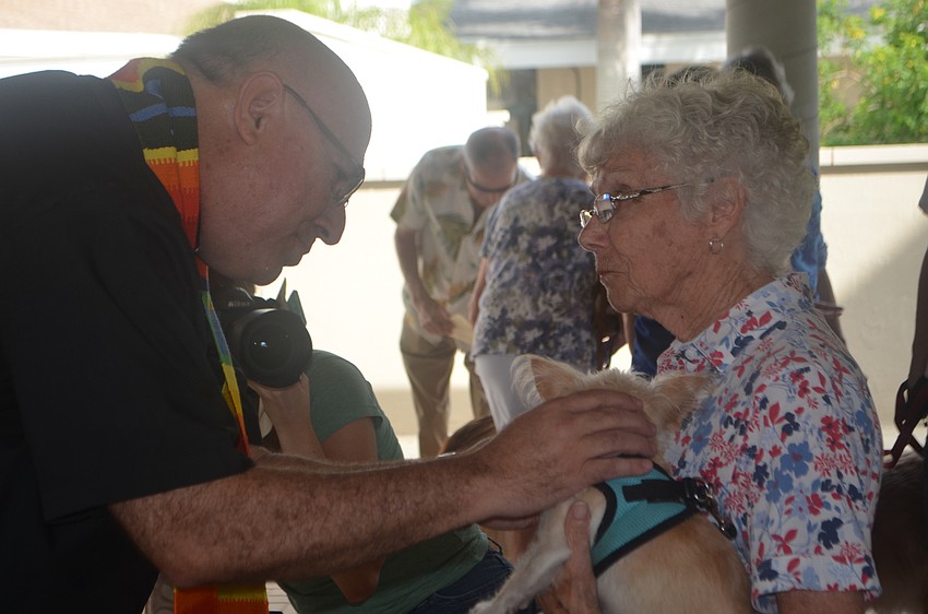 Reverend Wayne Farrell blesses Lexi, a 7-year-old long-haired chihuahua, while her owner, Gray Davis, holds her.