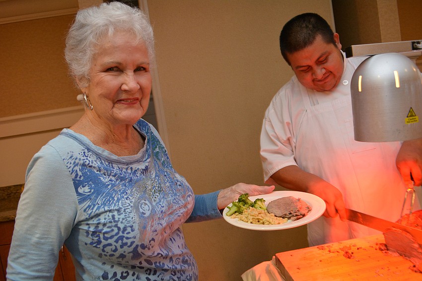 Joan Davis  has Andreas Lugo add some sourbraden, a marinated meat, to her plate. She used to eat it with her grandparents.