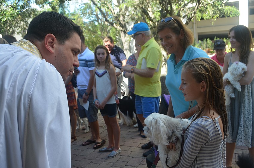 Father Chris Wood greets Liza Strong, 10, and her maltese, Scooter, 2.