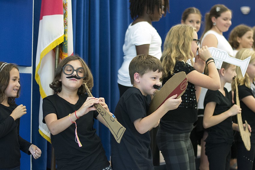 Members of the Bay Haven chorus and percussion ensemble mime playing instruments during a performance to celebrate the school's 90th anniversary.