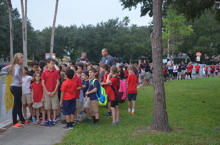 A mass of students and parents line up to safely cross the crosswalk on National Walk to School Day.
