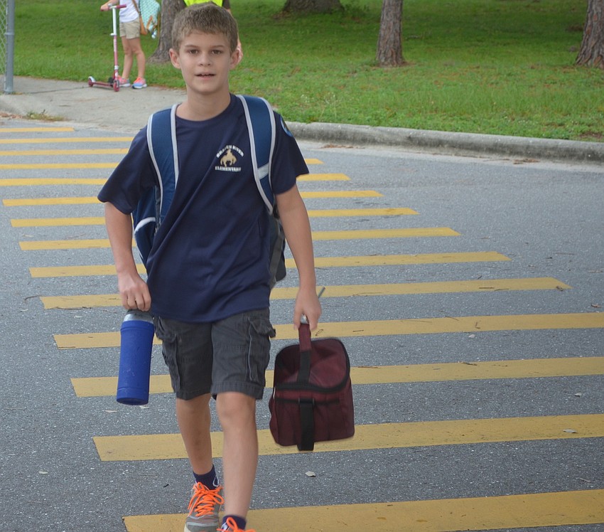 Bradenton's Kameron Davenport, 11, carries quite the load as he power walks across the crosswalk toward Braden River Elementary on National Walk to School Day.