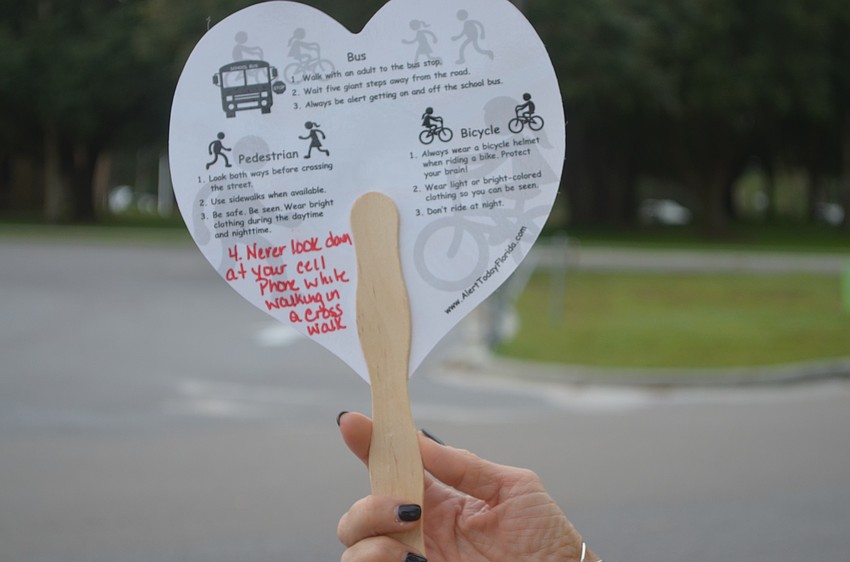 Alert Today Florida's Melissa Wandall holds a safety sign that she passed out to students participating in National Walk to School Day.