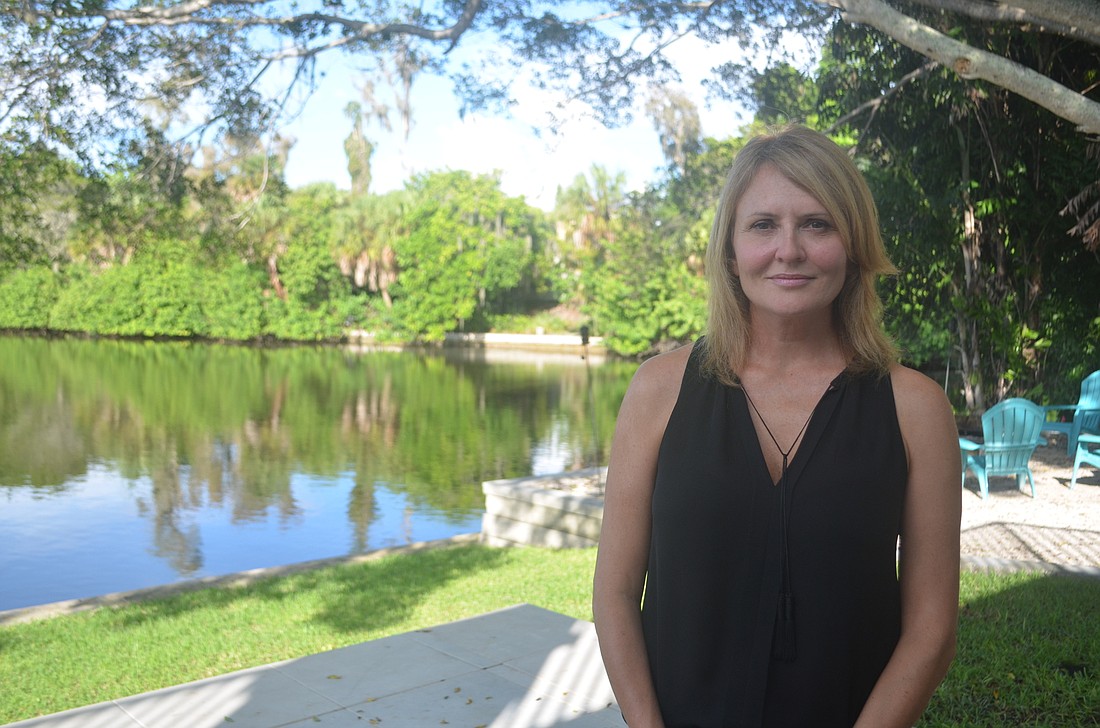 Lorie Tiernay stands on her back deck directly across the canal from the Siesta Key wastewater facility.