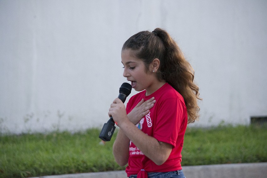 Phillippi Shores alumna Mia Petrov performs the national anthem before the start of the race.