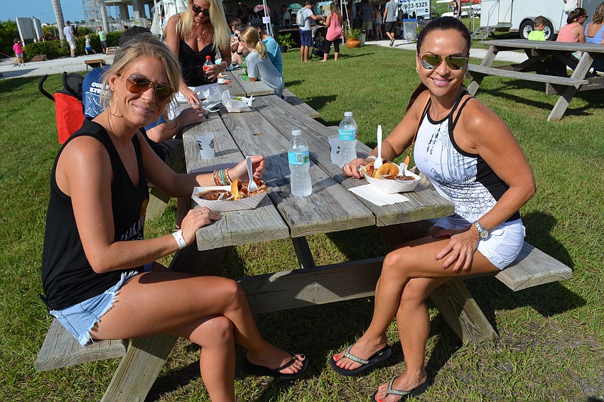 Lakewood Ranch's Kristi Ford tries pulled pork and baked beans from TK Grill with friend Myhanh Kaas, of Sarasota.