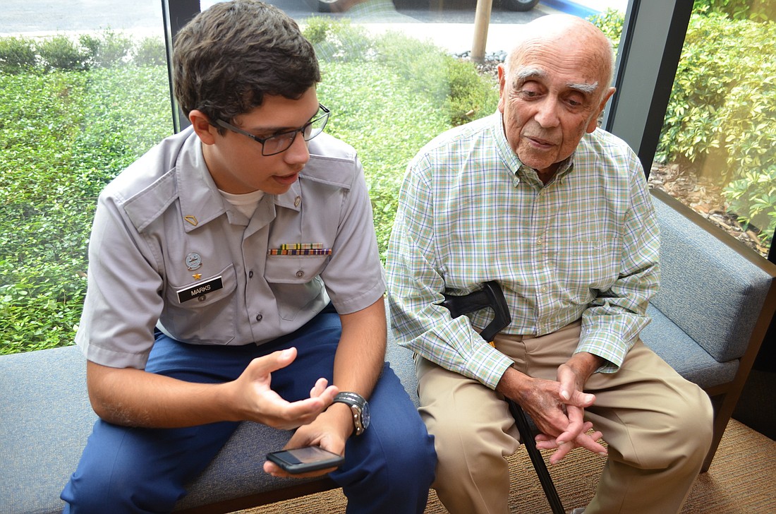 Sarasota Military Academy junior Ethan Marks guides Plymouth Harbor resident Charles Gehrie through programing a contact in his iPhone as a member of the eTEAM.