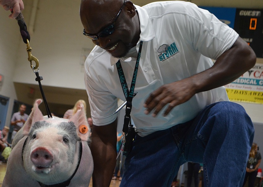 Louis Jackson, who oversees in-school suspension, gets ready to smooch Batpig, the FFA Chapter pig.