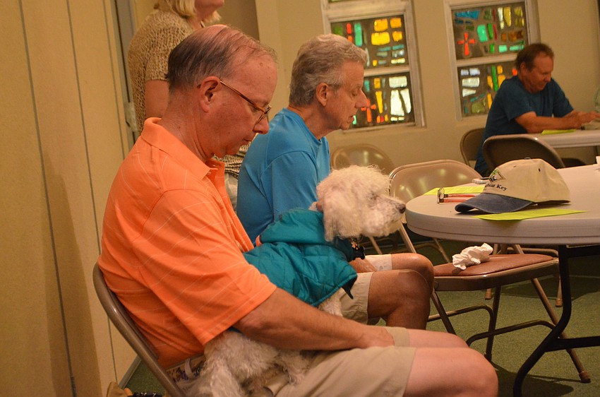 Raymond Smith and Snowball, 12, listen to Pastor Eric Wogen during St. Armands Key Lutheran Church’s annual pet blessing on Oct. 15.
