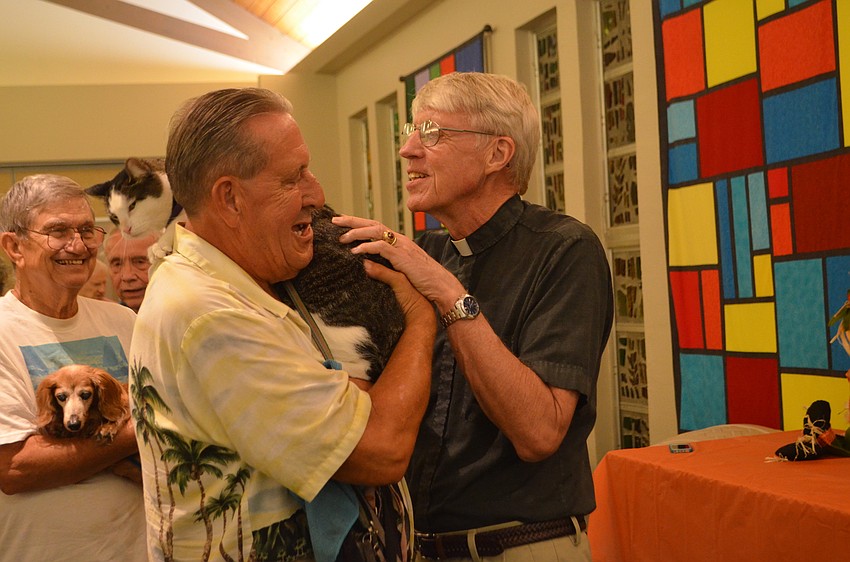 Pastor Eric Wogen blesses Acorn, 12, with owner Dan Ehrbar.