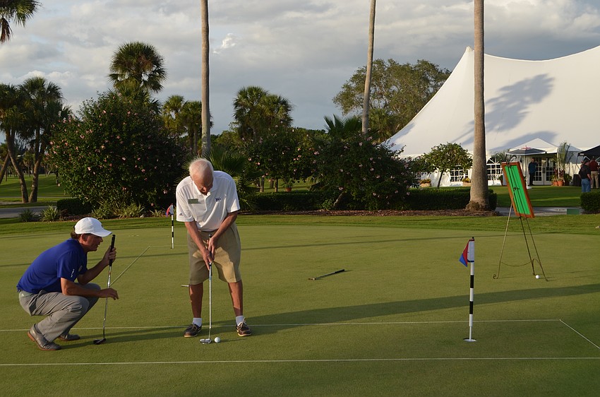 Terry O’Hara, golf director for the Longboat Key Club, helps Jack Daly during the OPL Putting Challenge.