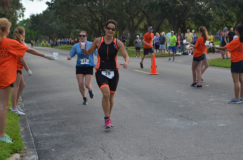 Valerie Berger grabs a cup of water as she begins the running portion of the Longboat Key Triathlon.