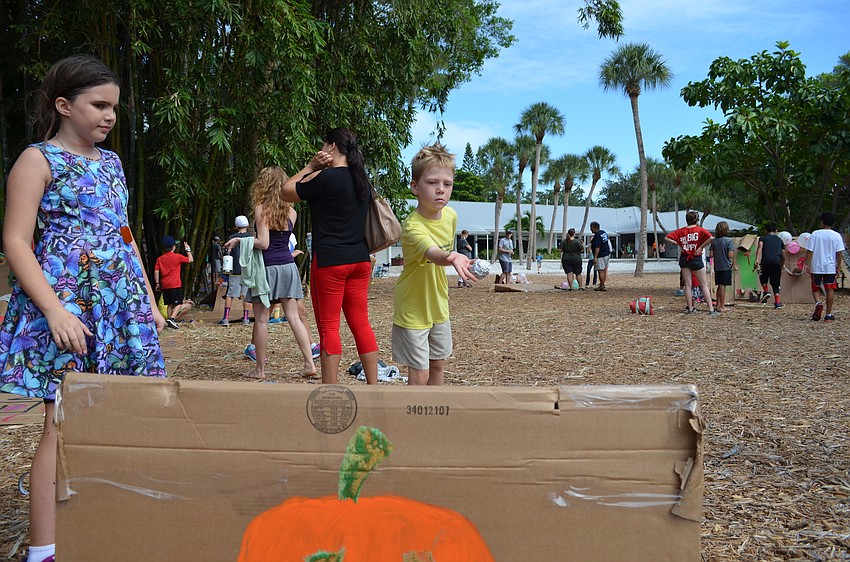 Bella supervises her cardboard arcade game as Erik plays.