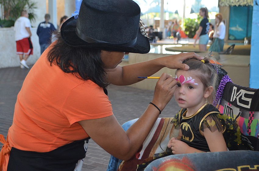 Makenna Lee, 3, gets her face painted by Akiko at Mote’s Night of Fish, Fun and Fright