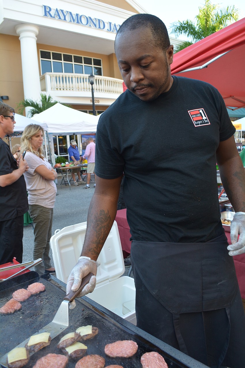 J.R. Jefferson adds cheese to mini hamburgers served up free for guests by Square 1 Burgers.