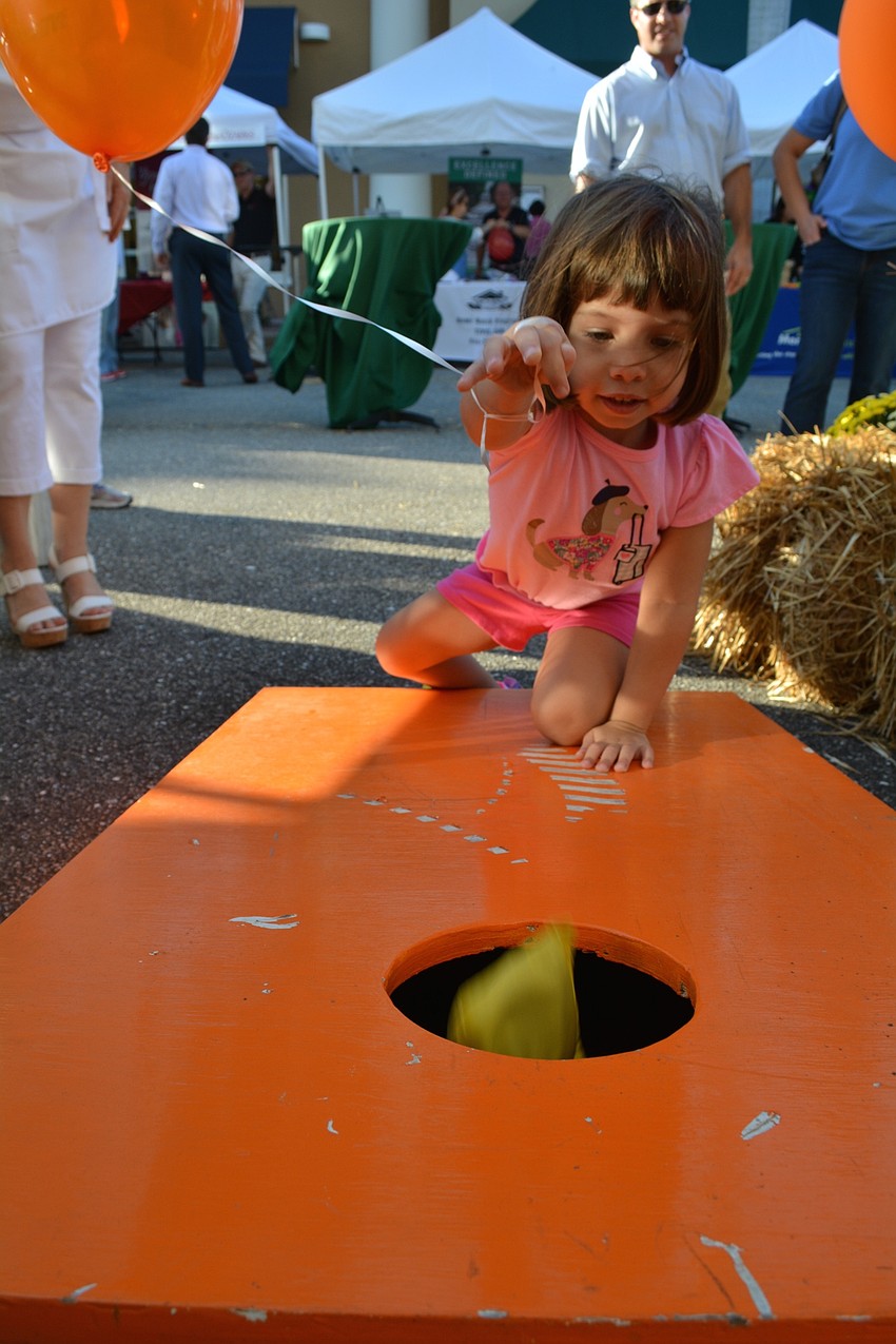 Holly Schwartz, 3, of Sarasota, tries her hand at a game of corn hole.