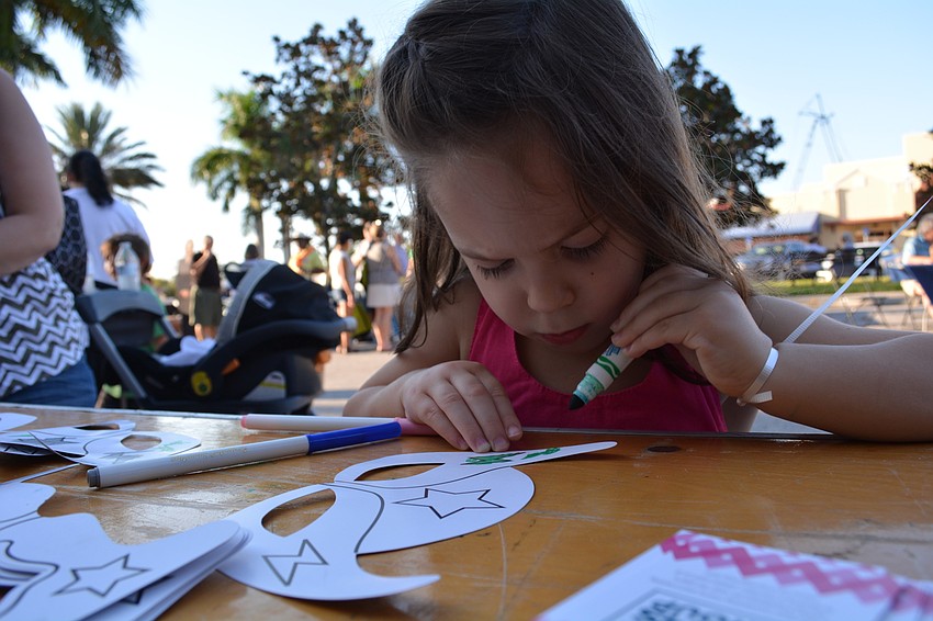 GreyHawk Landing's Alexandria Marcus, 3, colors at a Club Day booth as her parents, Rachel and Neil, and new baby brother, Nathaniel, watch.