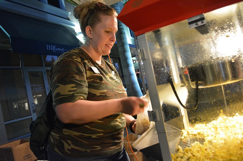 Melissa Kennedy, of Grow Financial Credit Union, keeps busy feeding popcorn to party-goers.