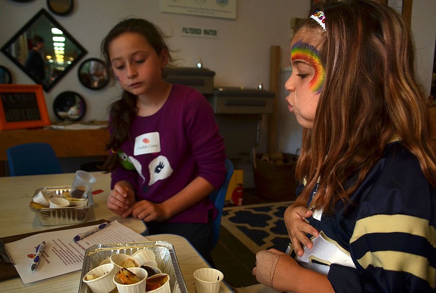 Zoe Korman (right) and Ava Gekht consider each of the challah entries. Their names were selected out of a hat, which gave the students the privilege of missing class to participate in the event.