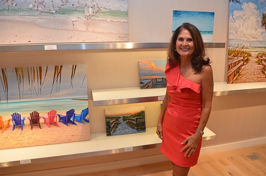 Local artist Mary Lou Johnson poses by a few of the many of her paintings that were available through the event raffle.