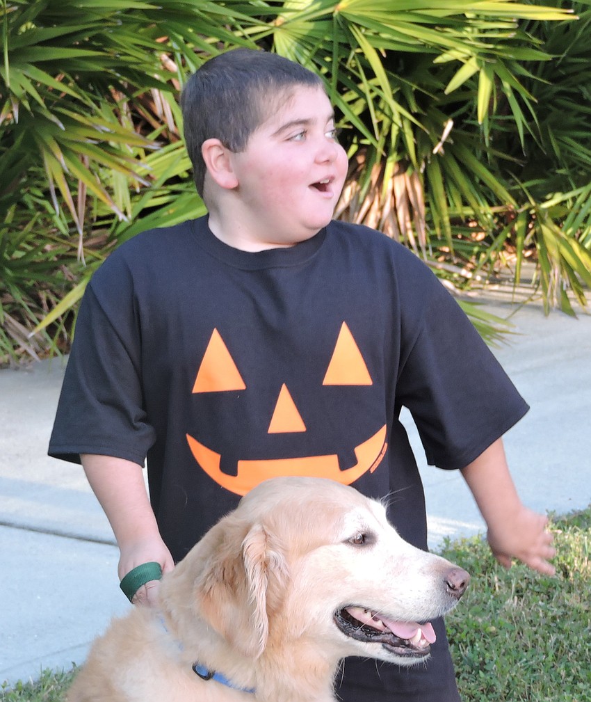 Grayson Tullio waits for the start of the Boo Run with his service dog, Hooch. The race, 