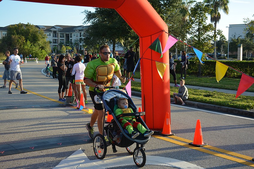 Lakewood Ranch's Sean Gast begins the race pushing his 18-month-old son, Brayden, in a stroller. Sean and Brayden dressed as Mutant Ninja Turtles.